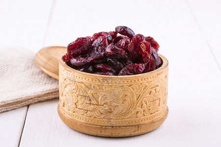 甜的烹饪在一个木杯里用白桌上盖着子和布满花边的木杯中干燥红莓桌子图片