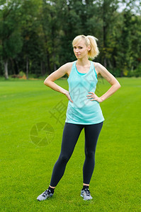 拉紧在职的年青女子站在草地上身体健康站立在草地上女图片