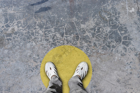 站在黄色圆圈的上下脚顶站在公共空间概念的地板上练习社交间距身体的感染站立图片