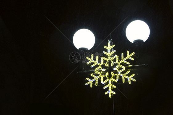 圣诞夜灯柱上的人物和新年冬季节日灯花环在城市公园的雪花形状节日灯环在城市公园的雪花形状节日灯美丽支柱象征图片
