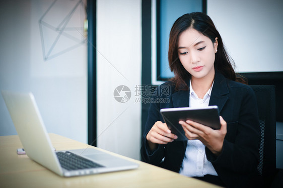 技术女士坐着使用平板在办公室工作放松时间和微笑的亚洲商业妇女图片