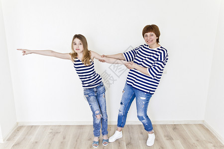 有条纹的最幸福母亲和女儿穿着条纹衣服在白墙附近玩十二垂直的图片