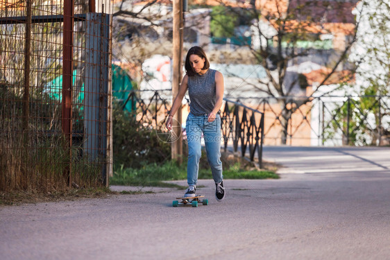 凉爽的年轻溜冰女青骑在村里长板上穿着散衣自由概念现代的畅快图片