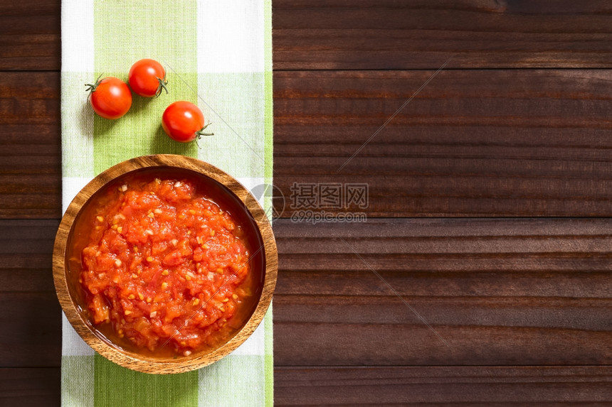 饮食由新鲜番茄大蒜干红菜和盐制成的意大利传统马里纳拉或波摩多罗番茄酱在木碗中供应边有樱桃西红柿用自然光照黑木头简单的图片