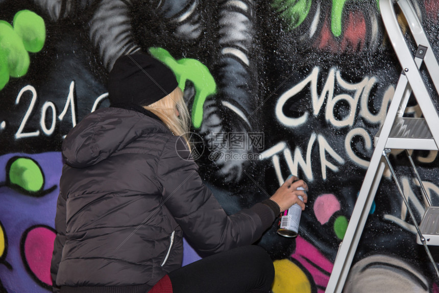 创造力建筑学喷涂在公共城市墙壁上的年轻女孩街头艺术家喷涂在公共城市墙壁上的年轻女孩街头艺术家能够图片