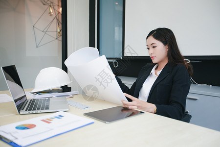 工人会议作场所亚洲程妇女持有蓝图在办公室工作时顶着硬头盔的亚洲女工程师图片