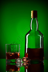 苏格兰冷冻威士忌瓶冰和玻璃绿色背景图片