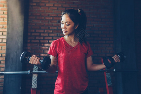 建造起重健美丽的肌肉适合女人锻炼肌肉和健身女人在房锻炼康生活方式的概念图片