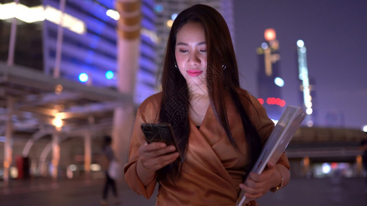 城市亚洲美丽的商业年轻女青在夜市街上使用智能便士走路亚洲人图片