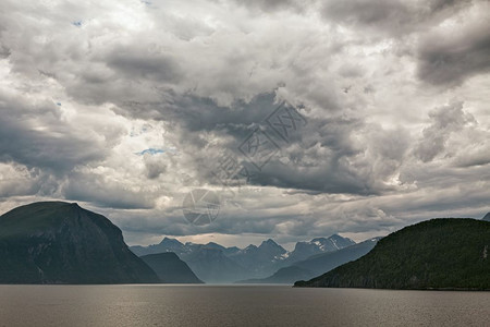 在多云的天空下挪威安道尔尼斯附近的Romsdalsfjorden沿线的山脉挪威安道尔尼斯附近的沿线风景爬坡道图片