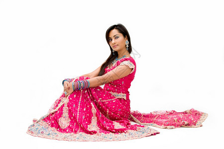 粉色的美丽Bangali新娘穿着色彩多的裙子坐着与世隔绝面纱蓝色的图片