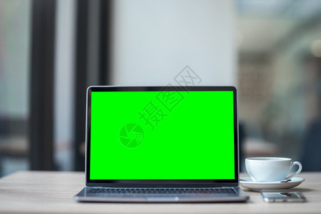 现代的办公室在线咖啡店背景桌子上用空屏幕咖啡杯和智能手机抽装笔记本电脑绿色屏幕图片