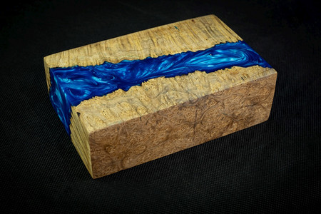 投掷抽象的在黑色背景上种下带有自然圆木的蓝环氧树脂工艺图片