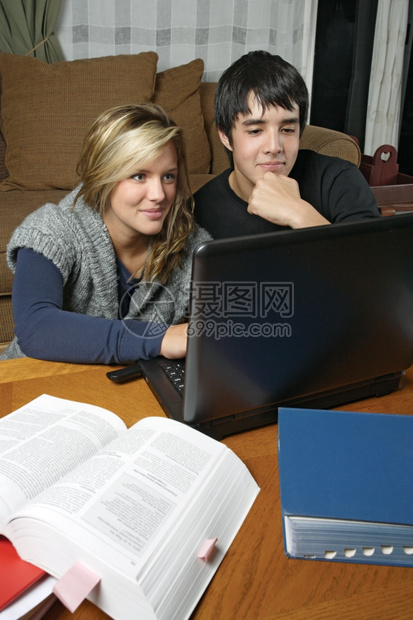 教育他们的女士两个学生和朋友使用笔记本电脑做家庭作业图片