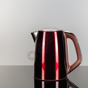 厨具现代的红色涂有不锈钢无绳电水壶灰色镜面背景上有棕色塑料手柄有复制空间灰色镜面背景上有红色不锈钢水壶图片