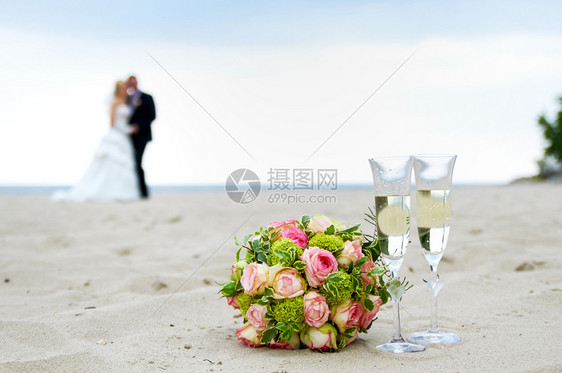 浪漫的快乐海岸线婚礼花束和一对夫妇在海滩上图片