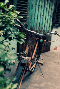 植物群怀旧令人惊叹的关闭旧式自行车前门古老房子车轮生锈在越南城镇以古代语调为模糊背景损坏天图片
