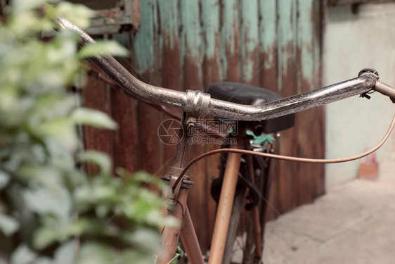 古老的令人惊叹关闭旧式自行车前门古老房子车轮生锈在越南城镇以古代语调为模糊背景损坏古董印象图片