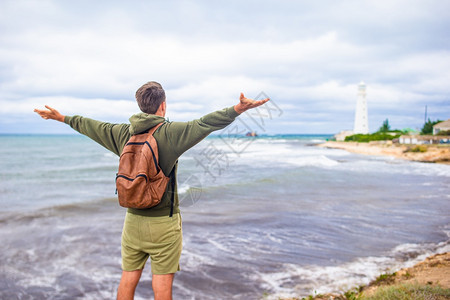 在风暴海岸附近的旅游者望着灯塔双人步行到灯塔天空海洋后部图片