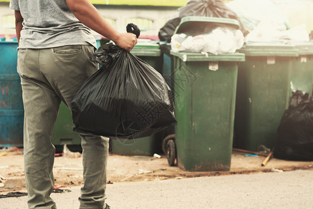 打扫生态成人妇女用手把垃圾装在黑袋里清洁成垃圾图片