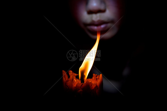 灯芯明亮的脸女人在黑色背景下吹蜡烛黑色的图片