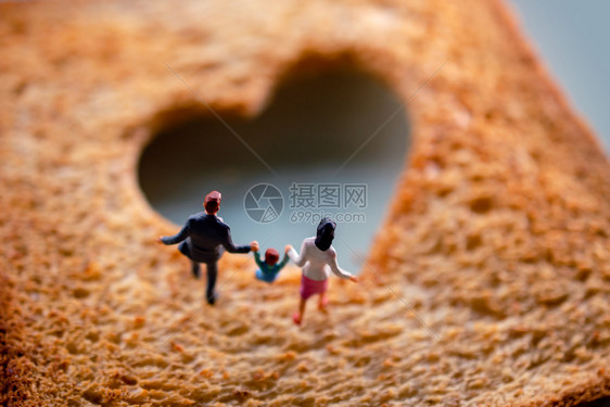 心折叠幸福家庭在烧伤的被焦烤面包上行走爱概念微型书图片