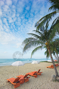 蓝色的夏天沙滩上橙色海椅和阳伞天空海面多云的蓝色天和大海加勒比图片
