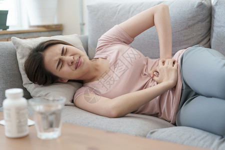 肚子月经期和疼痛的亚洲女在睡沙发上痛苦的年轻妇女在家中睡觉时抽筋淑女胃图片