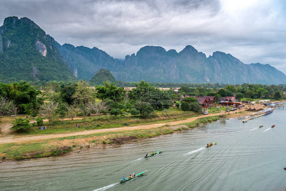 河边皮艇万老挝VangVieng的南宋江旅游船和山背景象图片