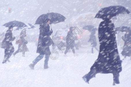 进入城市内人们向冬季暴风雪中移动在城市内爆发暴风雪晚上步行图片