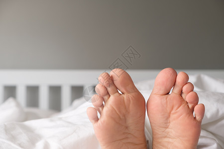 脚趾清晨一个女人的脚躺在白床上家毯子图片