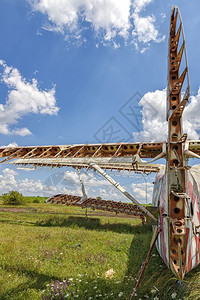 老的金属一架废弃飞机的部分它站在田野上对着阴云的蓝色天空一种图片
