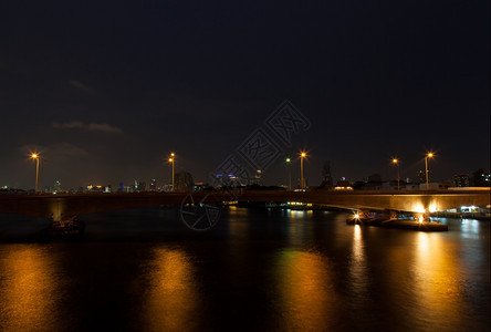 运动夜间穿过河桥有灯光照亮用电跑的汽车和河内桥梁船在旅行城市的图片