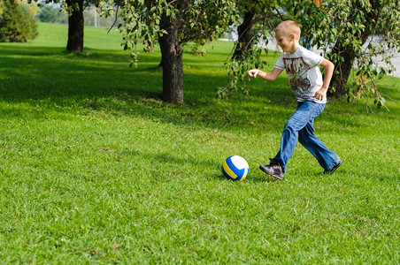 夏天小男孩在野外的草地上玩球俏皮足图片