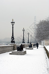 墙在英格兰伦敦泰晤士河边雪中行走的单人阴沉英国背景图片