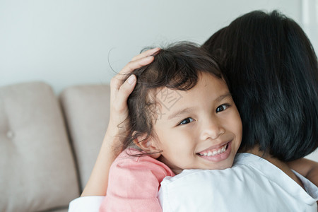 有女儿和母亲的亚洲家庭彼此拥抱相爱的亚裔女孩面带笑容的亚裔女孩在母亲的怀抱中家庭与母亲和女孩他们通过拥抱互相爱护母肖像年轻的图片