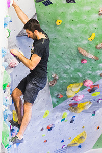强的一个人在室内造墙壁上攀岩活生方式和巨石概念的形成练习手图片