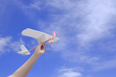 飞行玩具以蓝天为背景将橡皮动力飞机举在空中的儿童手握在空中灵感图片