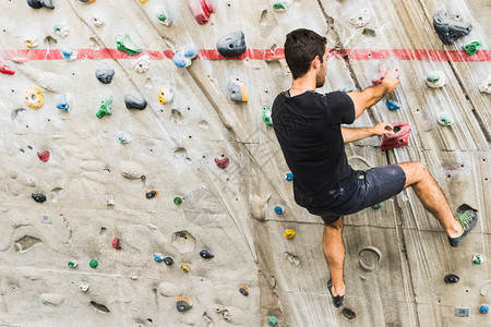 一个人在室内造墙壁上攀岩活生方式和巨石概念的形成抓锻炼悬崖图片