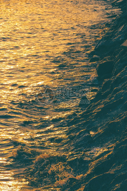 景观在海面上反射美丽的金色阳光在日落时沿海滩竖立垂直架状堆积岩石支撑时间图片