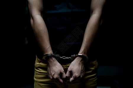 拘留贼犯罪一名囚被铐上手男囚犯在黑暗的监狱中被铐上手图片