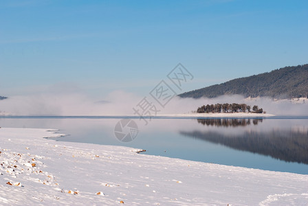 新的小路下雪湖岛和森林的冬季风景雾图片