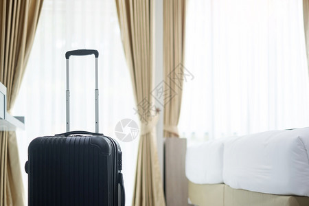 安全的舒适公寓现代旅馆房间的黑色行李有窗户帘和床幕及底背景旅行放松和休假概念的时间图片