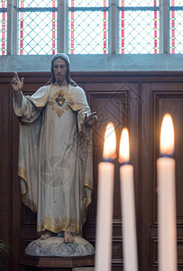 复活节祷告火焰基督在教堂的雕像与前方Lit燃烧蜡烛图片