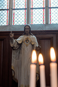 精神象征火焰基督在教堂的雕像与前方Lit燃烧蜡烛图片