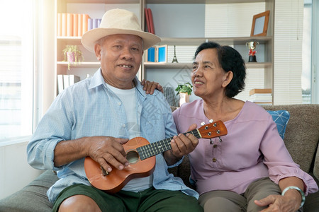 健康爱年长的快乐亚洲老年情侣在玩乌鲁列尔语在家里一起唱歌幸福退休后老年人的生活概念幸福退休后老年人的生活概念图片