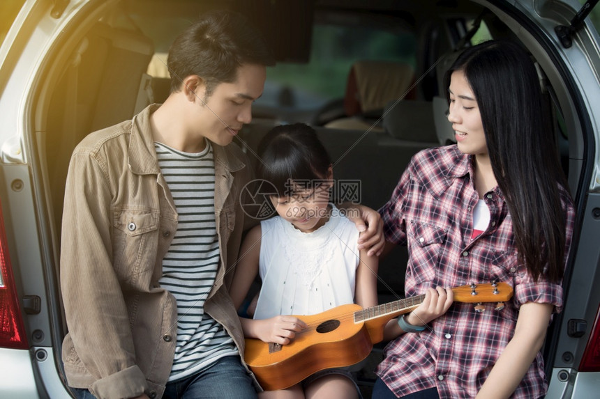 美丽的户外快乐小女孩与亚裔家庭一起玩乌鲁莱尔语坐在车里享受公路旅行和暑假游客图片