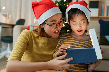 与母亲和女儿一起在家中渡假时一起打开圣诞礼物盒的亚洲幸福家庭惊喜女夜晚图片