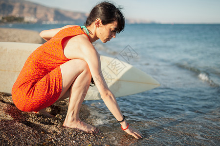 沙滩上年轻女孩带着冲浪板等着海浪图片