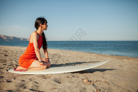 沙滩上年轻女孩带着冲浪板等着海浪图片